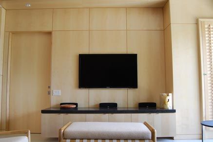 Minimalist living room with built-in wood cabinetry, a wall-mounted TV, and a simple bench seating area.