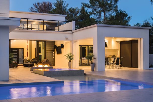 Text: Modern luxury home exterior with a pool, patio seating, and outdoor fire feature at dusk.